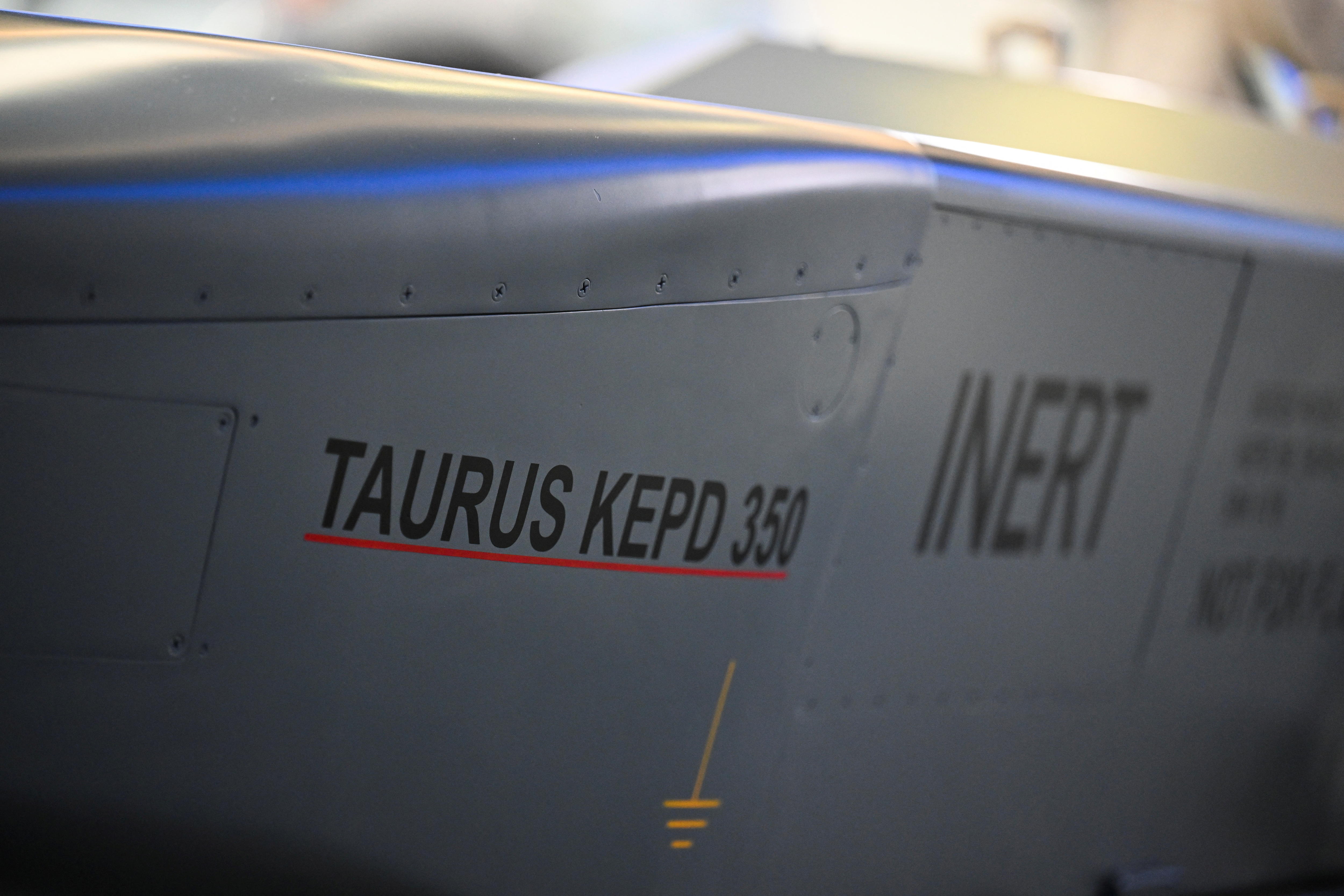 The side of a cruise missile with the Taurus logo and the word 'inert' next to it, on display in a showroom.