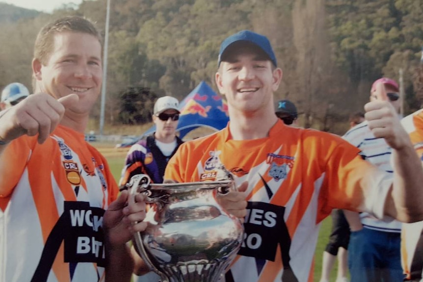 Brothers Scott and Jeremy Fittler hold a trophy after winning the football grand final in Lithgow