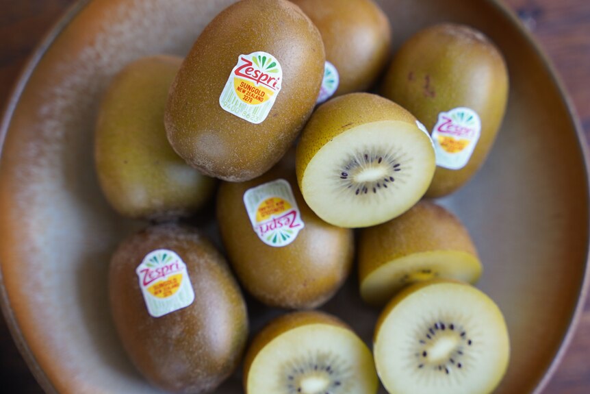 A plate of gold kiwifruits, some cut in half to reveal the yellow flesh. 