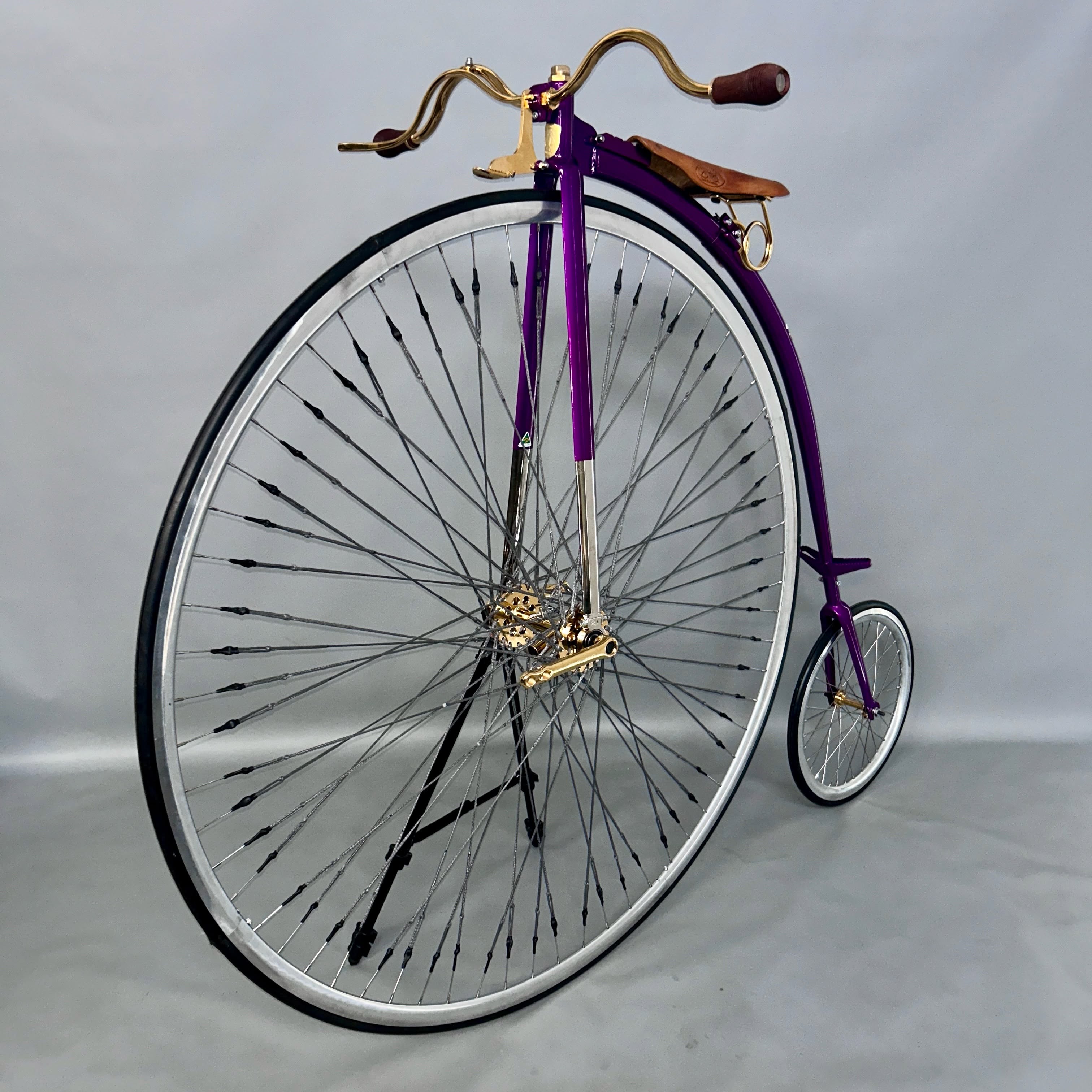 A purple penny farthing with gold-plated handlebars.