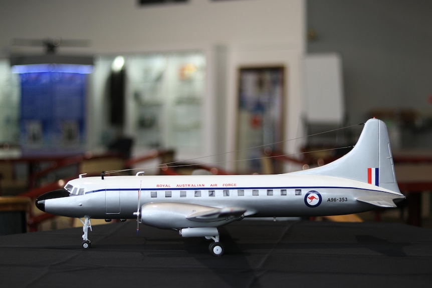 A horizontal, side on perspective of a silfer model aeroplane on a table.