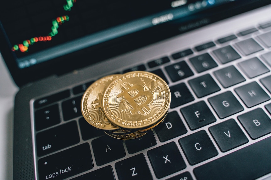 Three coins with the Bitcoin symbol sit on a laptop keyboard.