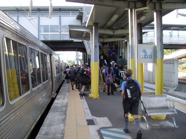 School children flooding the station platform as they disembark from the train.