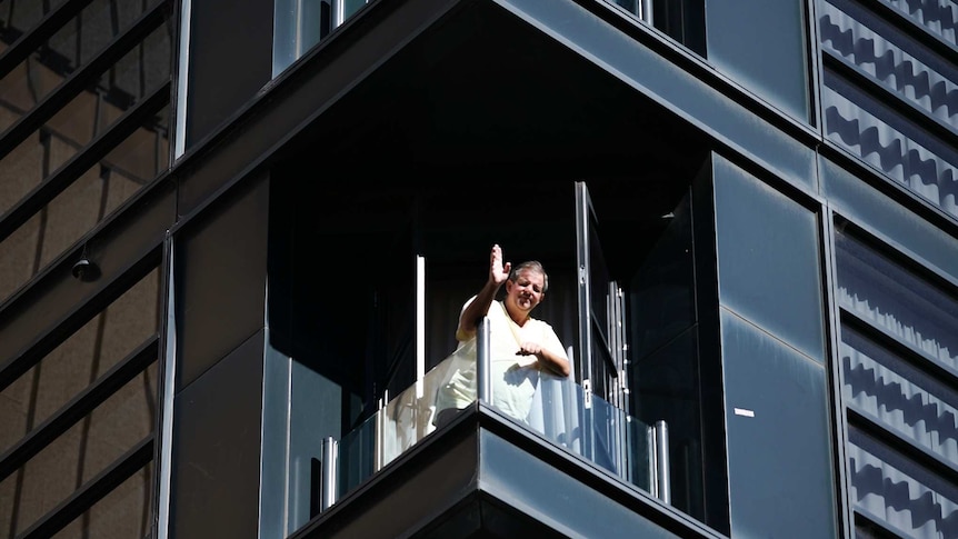 A man is waving from a balcony at Adelaide's Waymouth Hotel while in quarantine on November 18, 2020.