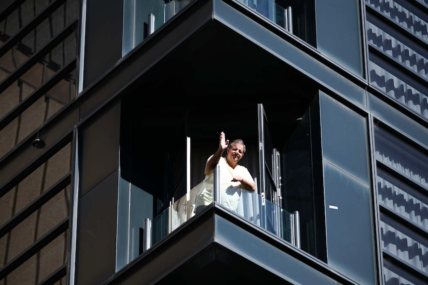 A man is waving from a balcony at Adelaide's Waymouth Hotel while in quarantine on November 18, 2020.