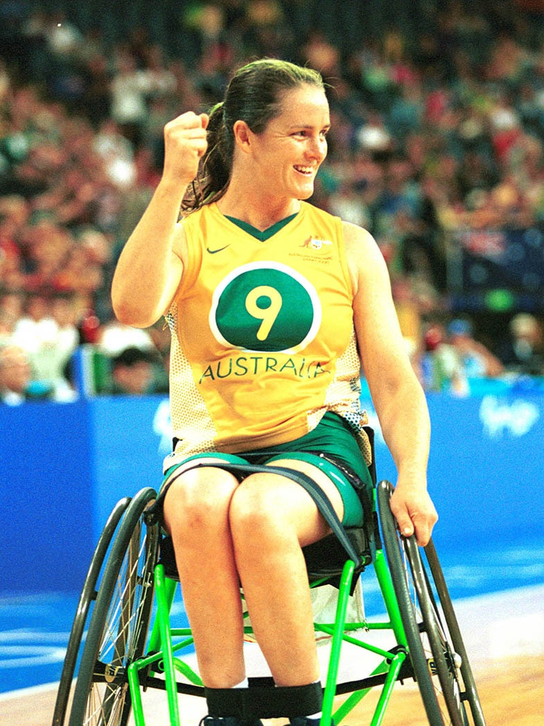 A woman playing wheelchair basketball fist pumps