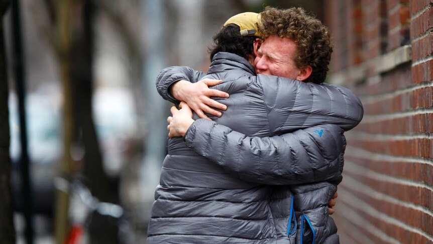 Men hug near Philip Seymour Hoffman's apartment