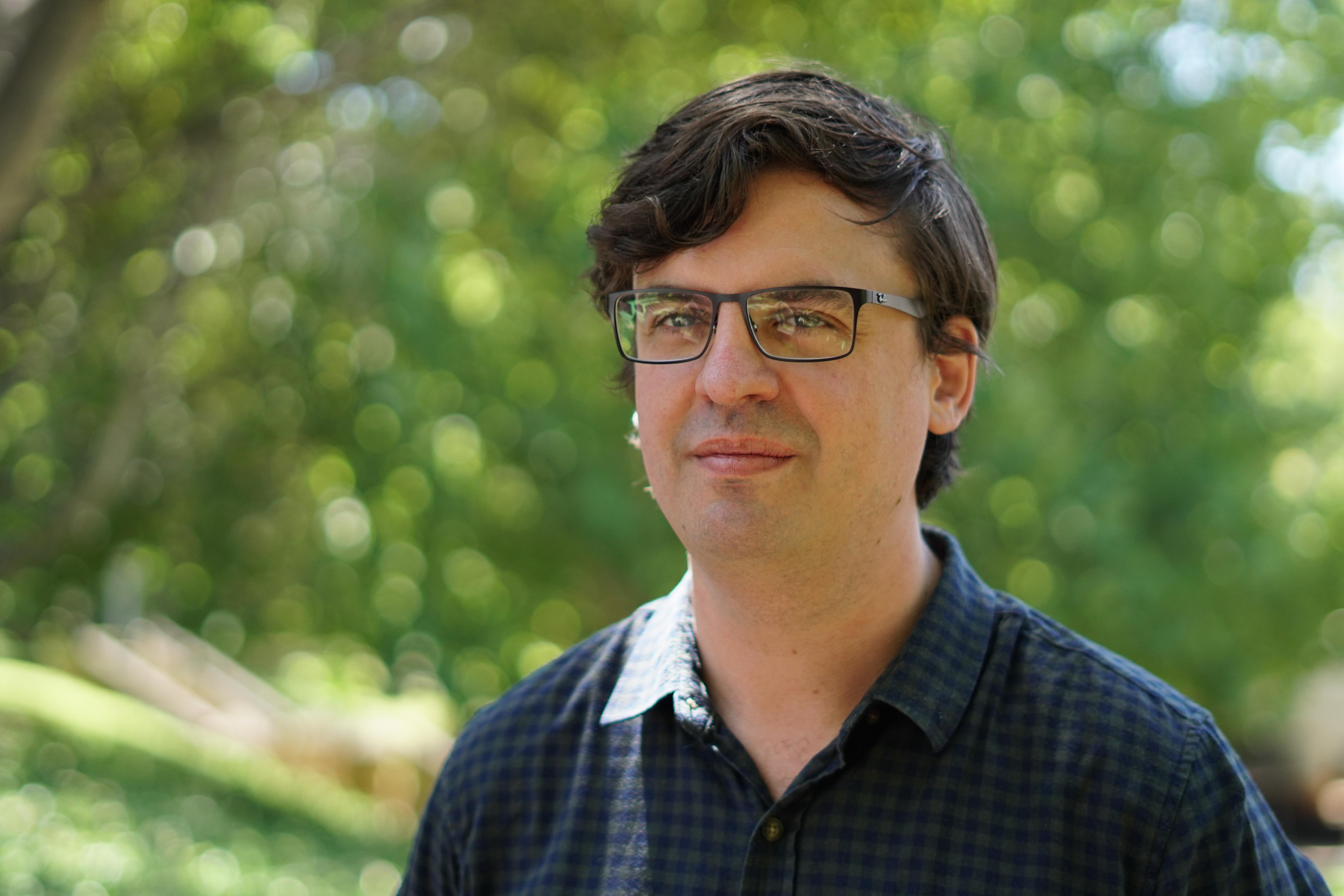 A head and shoulders shot of UnionsWA assistant secretary Owen Whittle outdoors wearing a blue shirt and spectacles.