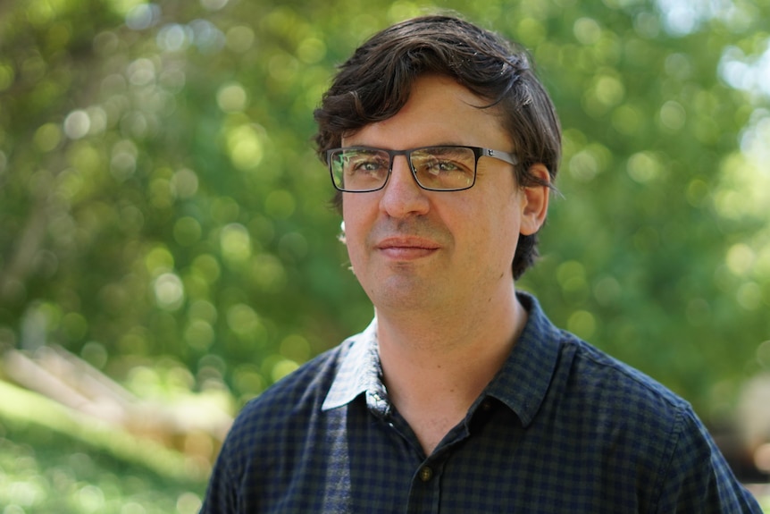 A head and shoulders shot of UnionsWA assistant secretary Owen Whittle outdoors wearing a blue shirt and spectacles.