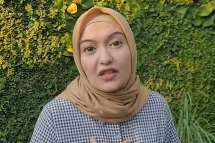 Woman wearing yellow headscarf looks at camera