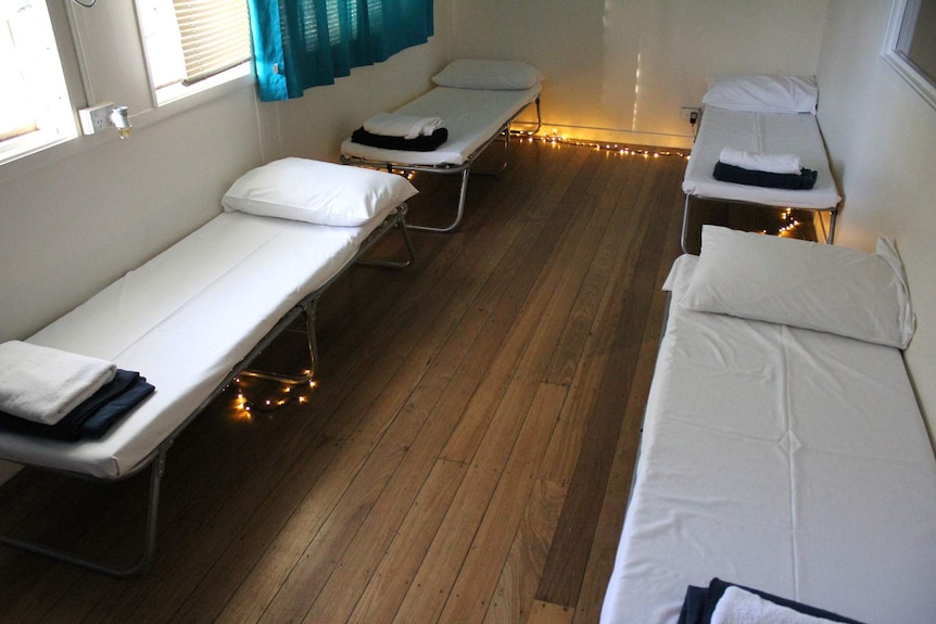 Camp beds with white sheets and fairy lights