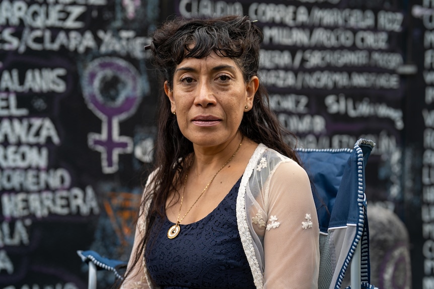 Araceli Osorio looks at the camera in front of a wall with women's named written on it.