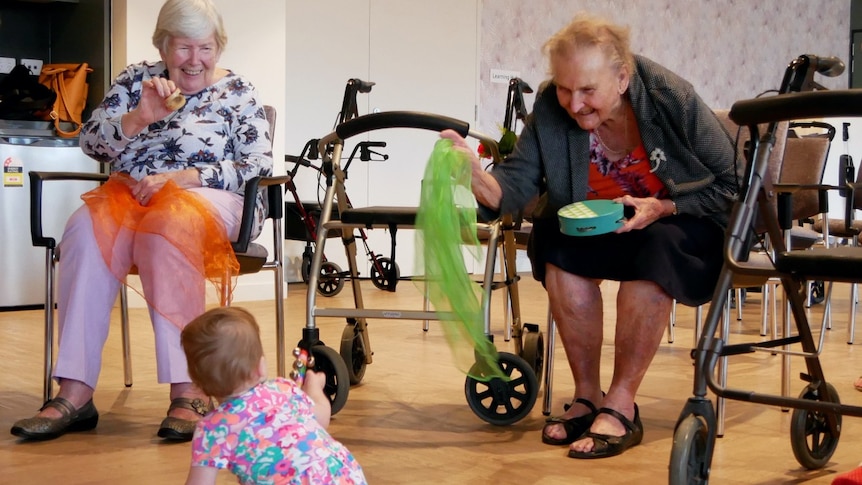 Two elderly women play with a baby during an intergenerational class. 