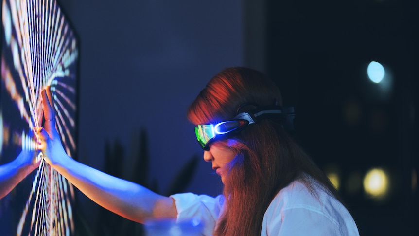 Young woman wearing augmented reality glasses touching screen with hands