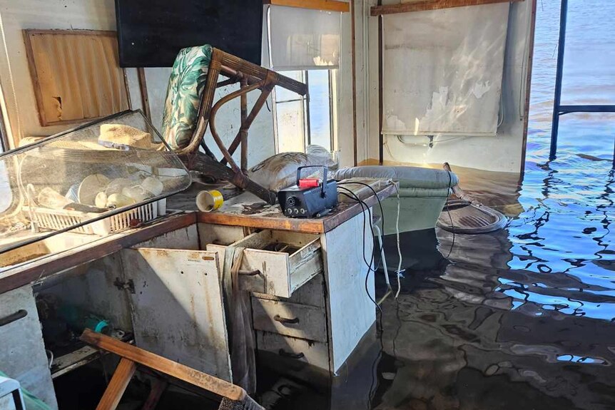 A scene of devastation inside the sunken houseboat, including a desk of drawers