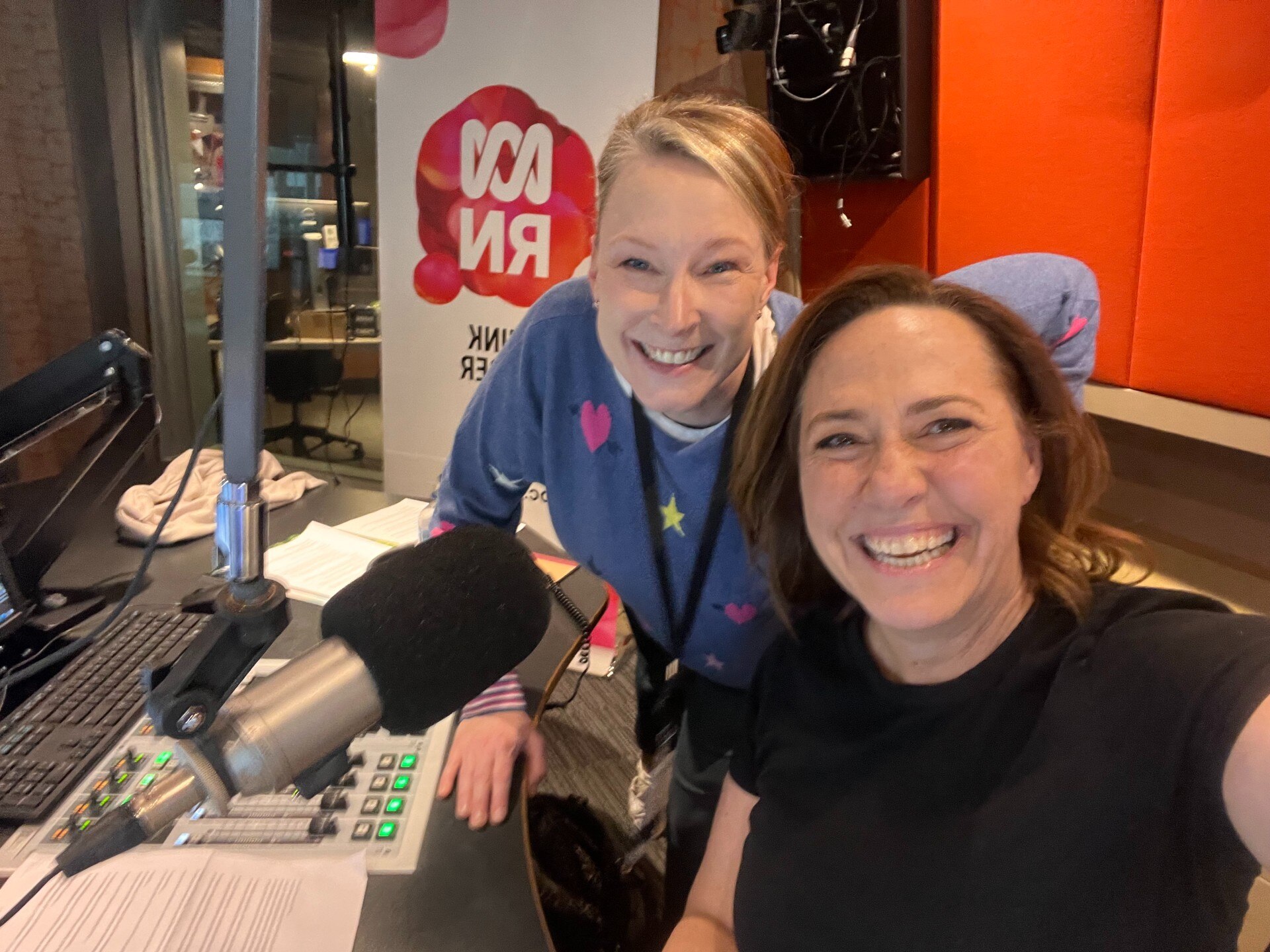 Two women in a radio studio smiling to camera.
