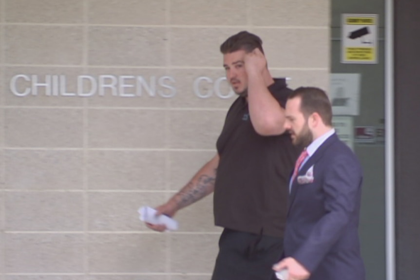 A burly man with tattoos leaves court.