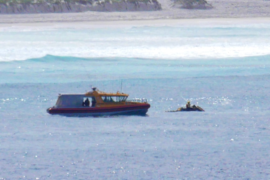 A search boat and a jetski resume a search for a missing man, with sand dunes in the background.
