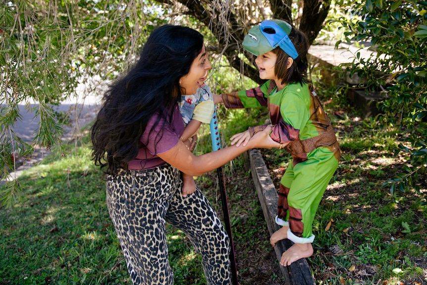 A woman playing with her son who's in a tree