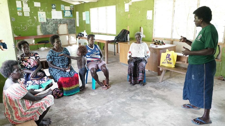 Five women sit in a classroom looking at Doreen Nauvana as she moves her hands and talks.