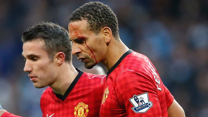 Robin van Persie helps Rio Ferdinand (R) off the pitch after the defender copped a coin to the face.