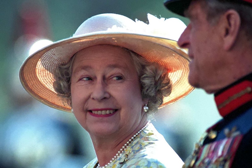 Regina Elisabeta a II-a se uită zâmbind la soțul ei, Prințul Philip.
