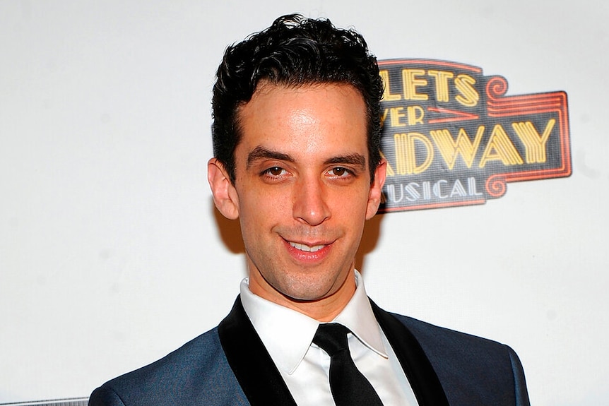 A picture of a man with dark hair in suit and tie smiling.