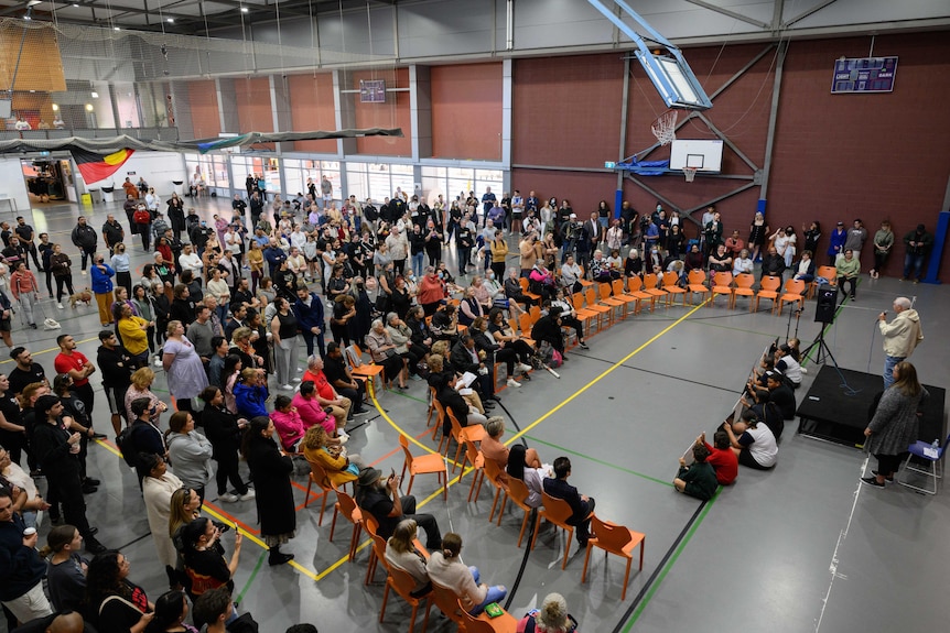 A group of people gather around a stage inside a hall