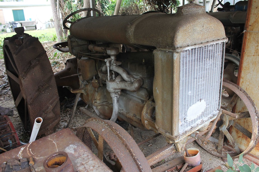 A rusty old tractor sits in a garage.