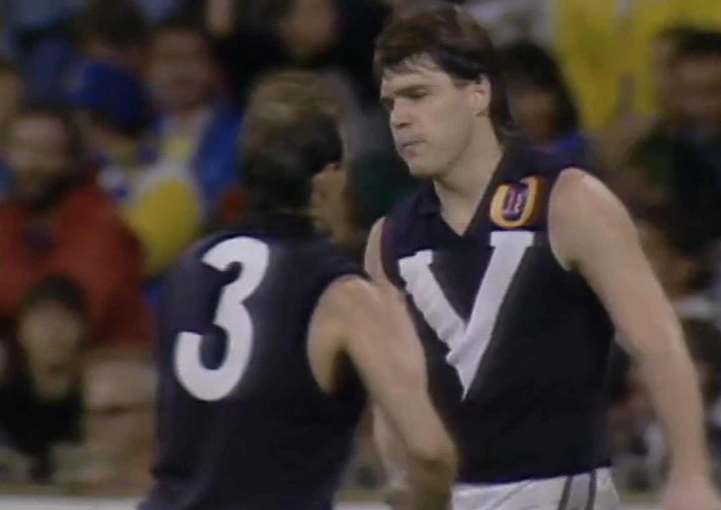 Jason Dunstall es felicitado por un compañero de equipo de Victoria en una imagen granulada. 