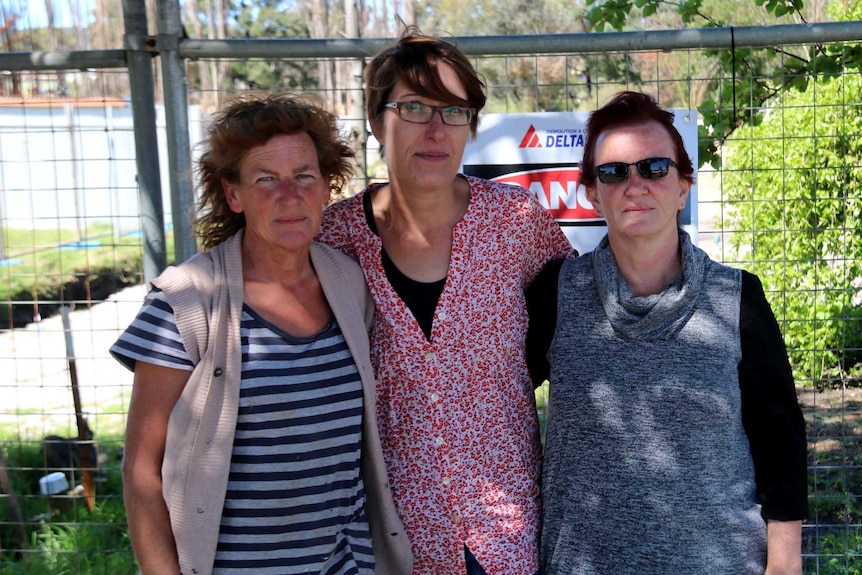 three ladies standing in front of a construction fence