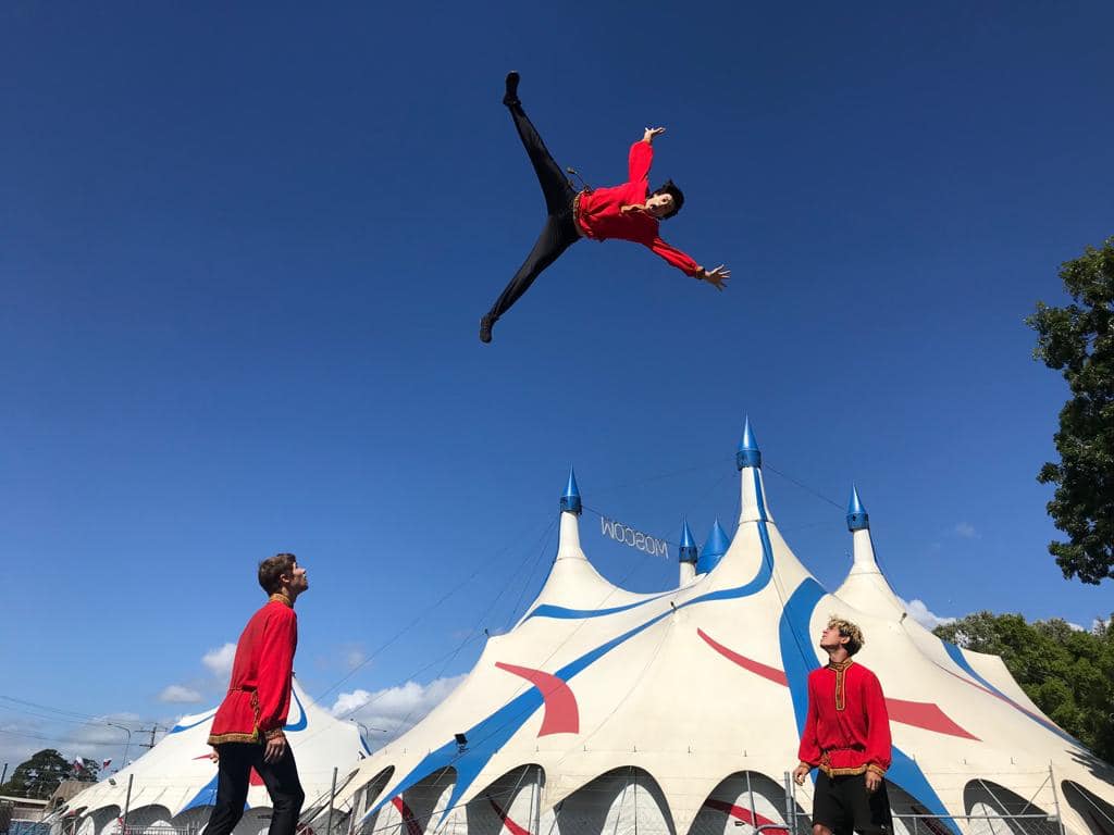 Un artista en el aire con carpas de circo debajo.