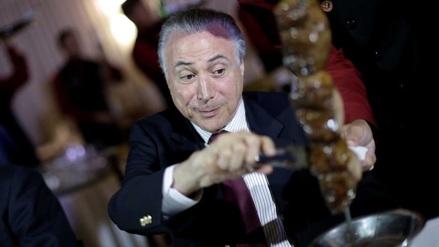 Brazil's President Michel Temer eats barbecue in a steak house.