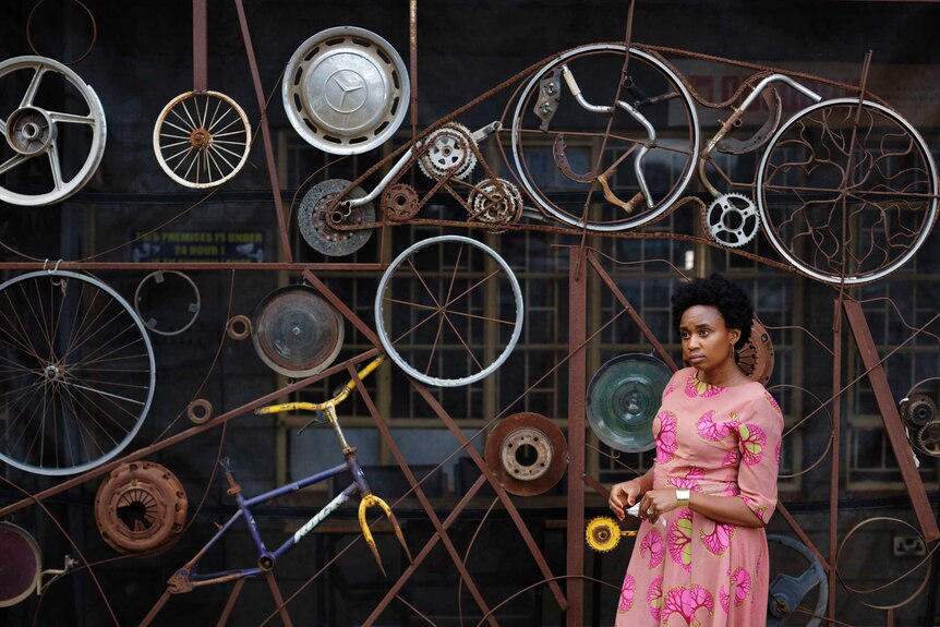 Wanuri Kahiu is seen posing in front of a wall of wheels.