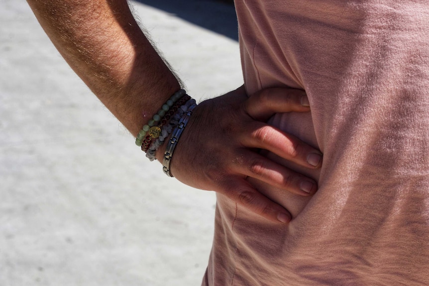 A hand on a hip. The wrist has some beaded bracelets.