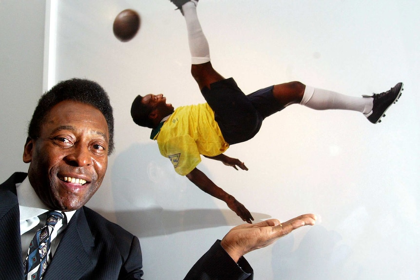 Pele poses next to his photo