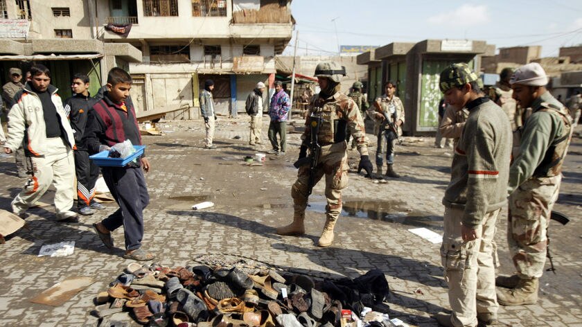 Iraqi soldiers inspect a pile of slippers which belonged to victims in a Baghdad suicide blast