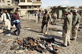 Iraqi soldiers inspect a pile of slippers which belonged to victims in a Baghdad suicide blast