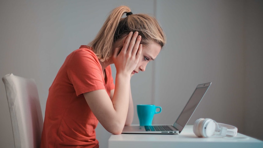 Woman looks at laptop screen, for a story about energy bill shock.