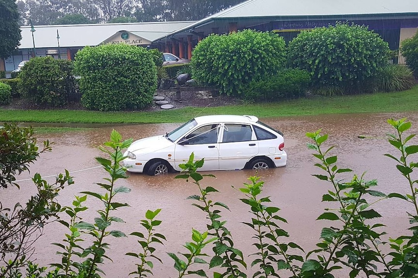 Stalled car tied with rope in floodwaters.