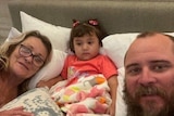 Adelynn in a bed with her uncle and grandmother.