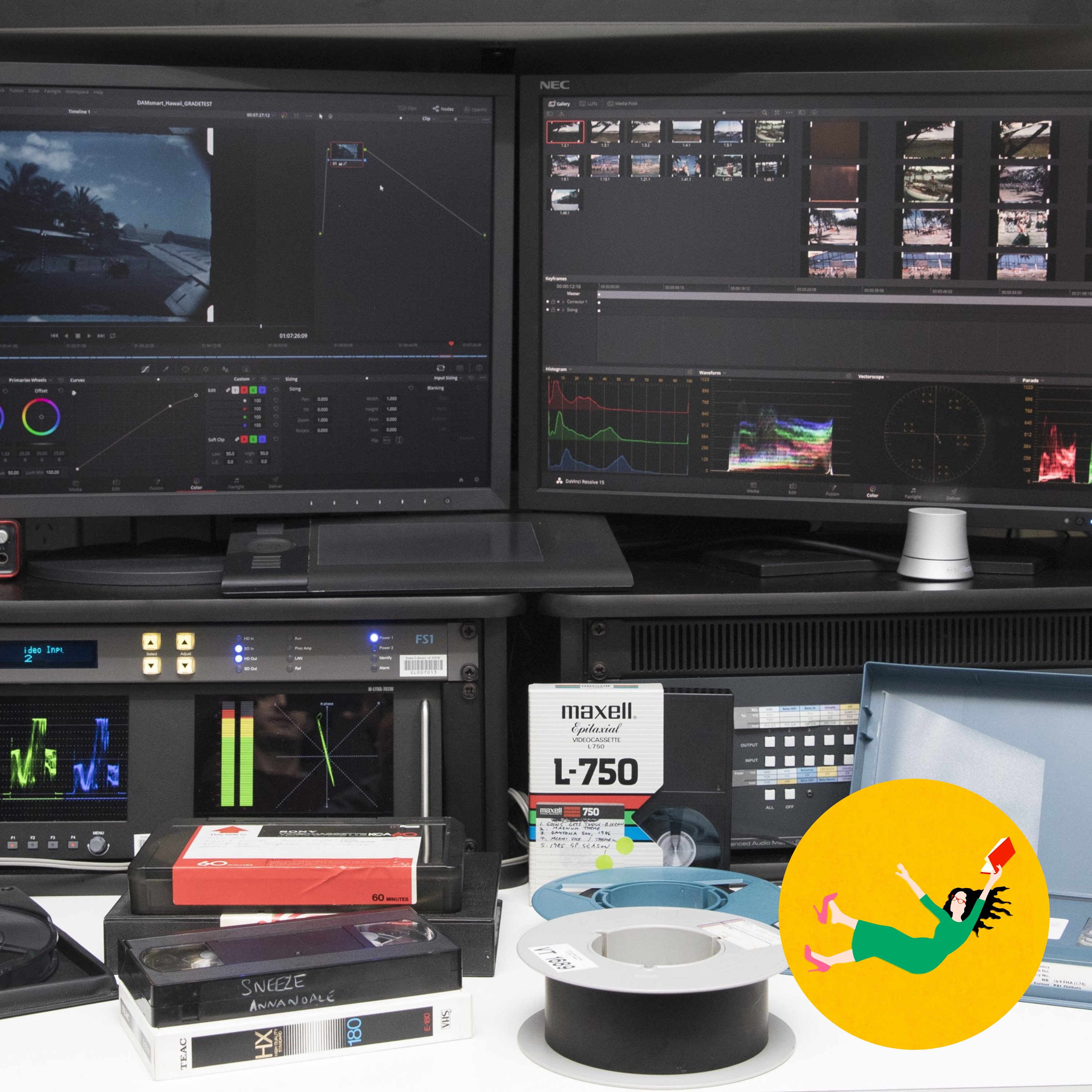 Dual monitors show video editing interfaces with waveforms and thumbnails. VHS, Betamax tapes, and an open reel are below.