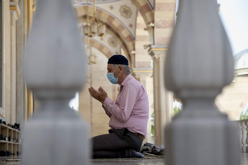 A Muslim man knees for prayer in a mosque