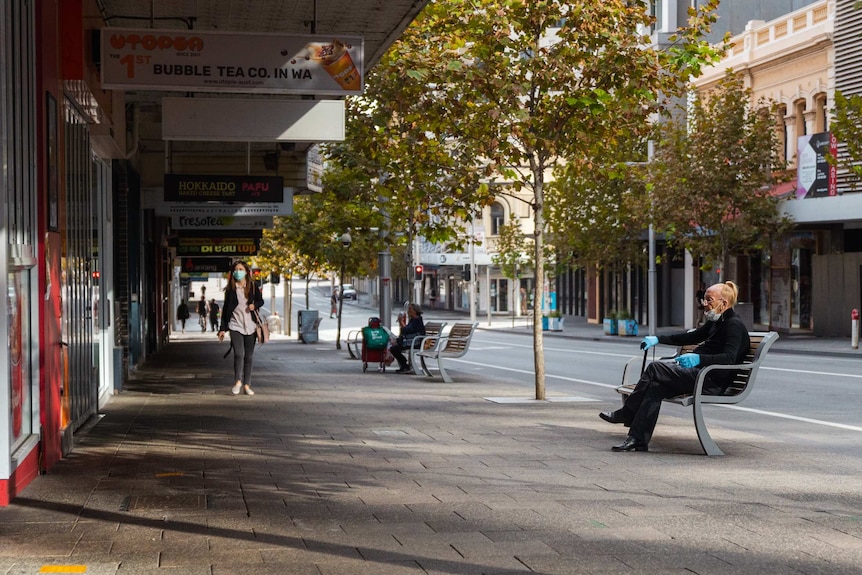 People wear gloves and masks in an almost deserted street in Perth's CBD.