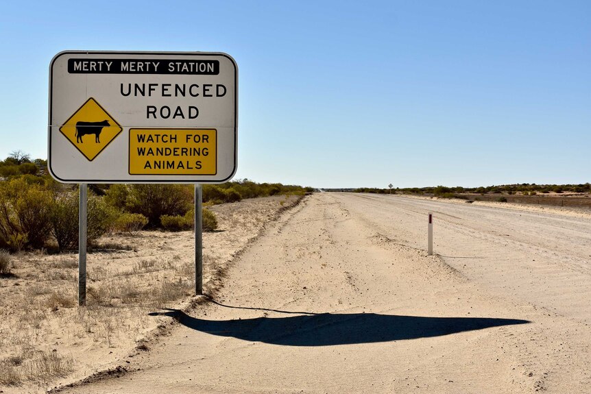 A large sign which marks the boundary of Merty Merty Station sits on the side of a white dirt road which has been graded.