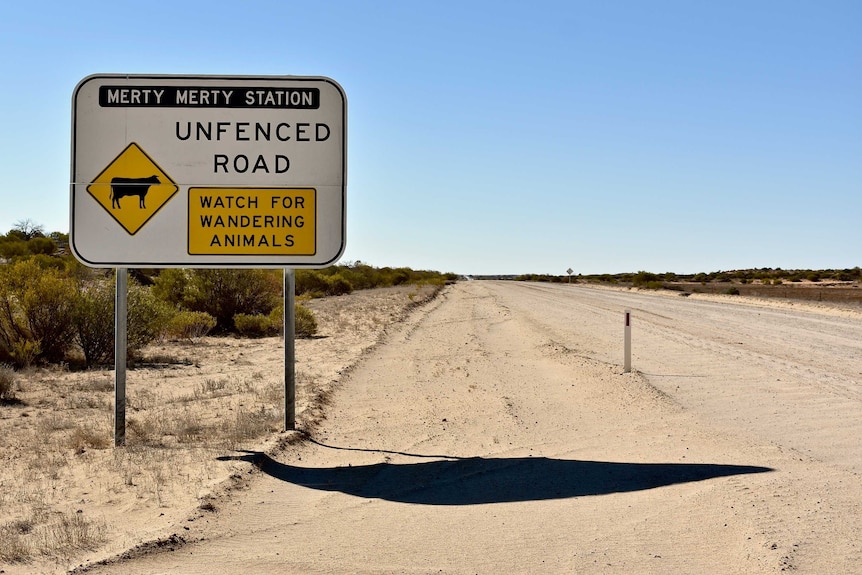 A large sign which marks the boundary of Merty Merty Station sits on the side of a white dirt road which has been graded.