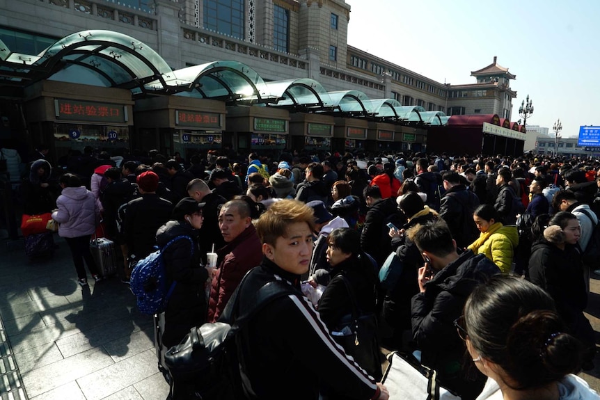 Hordes of people stand outside the train station in Beijing.