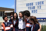 A group of five Chatswood High students in front of a 'good luck' sign.