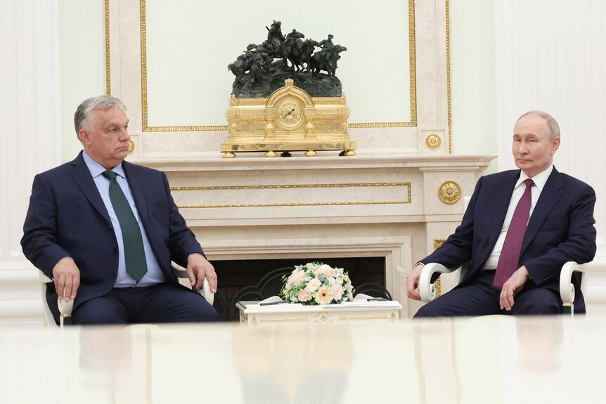 Viktor Oban and Vladimir Putin sit in chairs a short distance from each other.