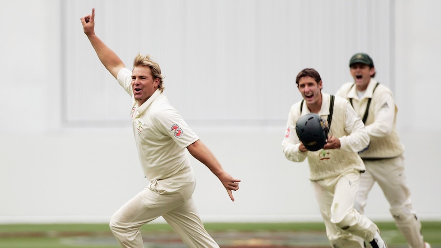 Shane Warne runs away from Michael Hussey and Adam Gilchrist as he celebrates his 700th Test wicket, against England at the MCG.